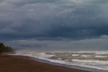 Dramatik gökyüzü ve fırtınalı bir denizde bir plajda Tortuguero Milli Parkı, Kosta Rika