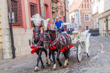 Krakow, Polonya - 3 Eylül 2016: At arabası ile turistler Krakow sokaklarında geçiyor.