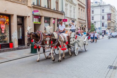 Krakow, Polonya - 3 Eylül 2016: At arabası ile turistler Krakow sokaklarında geçiyor.