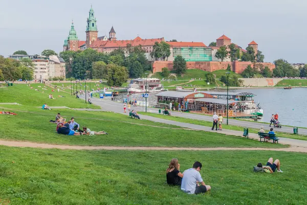 Krakow, Polonya - 4 Eylül 2016: İnsanlar Vistula Nehri, Krakow, Polonya Wawel Kalesi önünde oturmak