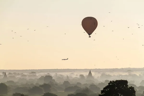 Balloon over Bagan, landing airplane and the skyline of its temples, Myanmar