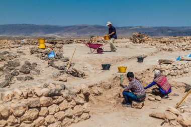 SALALAH, OMAN - FEBRUARY 25, 2017: Workers and archeologists at Sumhuram Archaeological Park with ruins of ancient town Khor Rori near Salalah, Oman clipart