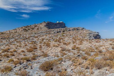 Umman'ın en yüksek dağı olan Jebel Şems yakınlarındaki Hacer Dağları manzarası. Arka planda askeri radar alanı.