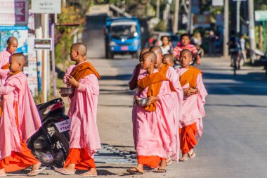 Nyaungshwe, Myanmar - 27 Kasım 2016: Genç Budist rahibeler Myanmar'ın Nyaungshwe kasabasında bir sokakta sabah sadakaları için gidiyorlar.