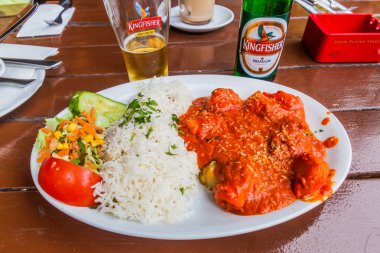 Berlin, Almanya - 12 Ağustos 2017: Kingfisher birası ile tavuk vindaloo yemeği.
