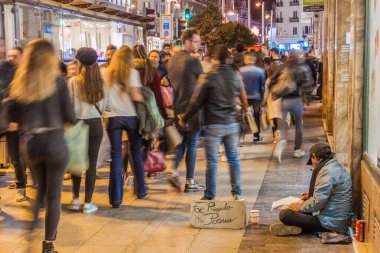Madrid, İspanya - 22 Ekim 2017 Calle Gran Via caddesinde yürüyen insanlar evsiz bir adamın yanından geçiyor. Tabelada 