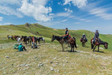 Song KUL, KYRGYZSTAN - 23 Temmuz 2018: Kırgızistan Song Kul Gölü yakınlarında at süren turistler