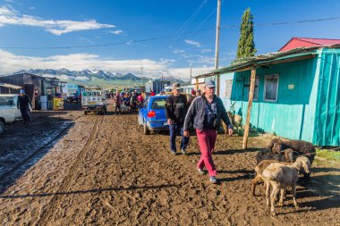 KARAKOL, KYRGYZSTAN - 15 Temmuz 2018: Karakol 'daki Pazar hayvan pazarında koyunlu yerel halk.
