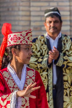 BÜKHARA, UZBEKISTAN - 30 Nisan 2018: Buhara, Özbekistan 'ın merkezinde geleneksel elbiseler giyen dansçılar