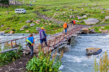 ALTYN ARASHAN, KYRGYZSTAN - 17 Temmuz 2018: Terskey Alatau dağ sırasındaki Arashan Nehri üzerindeki yaya köprüsü, Kırgızistan