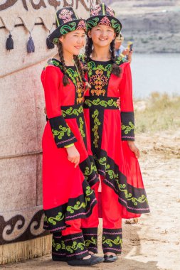 ISSYK KUL, KYRGYZSTAN - 15 Temmuz 2018: Kırgızistan 'daki Issyk Kul Gölü kıyısındaki Teskey Jeek Etnofestivali geleneksel elbisesini giyen yerel kızlar