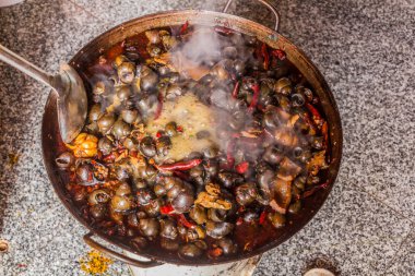 Çin 'in Hunan bölgesindeki Furong Zhen kasabasında bir restoranda tavada salyangoz pişirmek.
