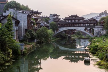 Hunan bölgesindeki Furong Zhen kasabasındaki bir nehre yansıyan eski köprü.