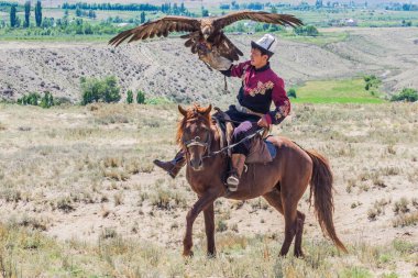 ISSYK KUL, KYRGYZSTAN - 15 Temmuz 2018: Kırgızistan 'daki Issyk Kul Gölü kıyısındaki Teskey Jeek Etnofestivali' nde kartalı olan yerel adam