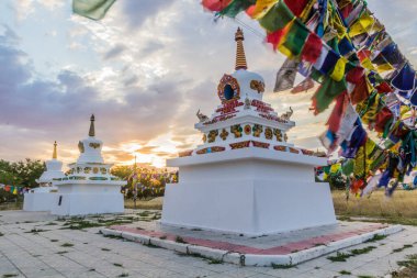 Stupas and flags near Syakusn Syume, Geden Sheddup Choikorling Monastery, Tibetan Buddhist monastery in Elista, Republic of Kalmykia, Russia clipart