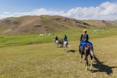 Song KUL, KYRGYZSTAN - 23 Temmuz 2018: Song Kul Gölü yakınlarındaki atlar üzerinde turistler