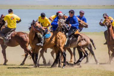 SONG KOL, KYRGYZSTAN - 25 Temmuz 2018: Yerel halk Son Kol Gölü kıyılarında düzenlenen Ulusal At Oyunları Festivali 'nde bir keçi leşi ile geleneksel bir at oyunu olan kok boru (ulak tartysh) oynuyor.
