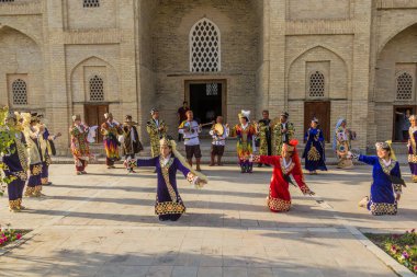 BÜKHARA, UZBEKISTAN - 30 Nisan 2018: Buhara, Özbekistan 'ın merkezinde geleneksel elbiseler giyen dansçılar