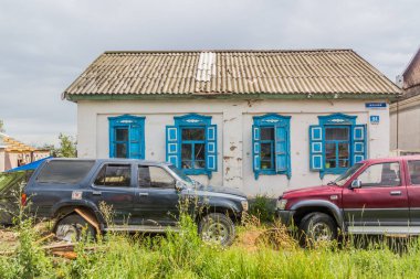 KARAKOL, KYRGYZSTAN - 14 Temmuz 2018: Karakol, Kırgızistan 'daki eski ev ve modern arabalar