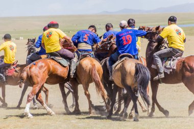 SONG KOL, KYRGYZSTAN - 25 Temmuz 2018: Yerel halk Son Kol Gölü kıyılarında düzenlenen Ulusal At Oyunları Festivali 'nde bir keçi leşi ile geleneksel bir at oyunu olan kok boru (ulak tartysh) oynuyor.