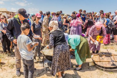 ISSYK KUL, KYRGYZSTAN - 15 Temmuz 2018: Kırgızistan 'daki Issyk Kul Gölü kıyısındaki Teskey Jeek Etnofestivali' nde insanlar lapa (soğanlı, havuçlu ve etli pirinç yemeği) yiyor