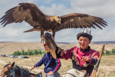 ISSYK KUL, KYRGYZSTAN - 15 Temmuz 2018: Kırgızistan 'daki Issyk Kul Gölü kıyısındaki Teskey Jeek Etnofestivali' nde kartalı olan yerel adam