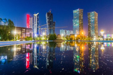 Kazakistan 'ın başkenti Astana' daki (şimdiki adıyla Nur-Sultan) gökdelenleri yansıtan akşam manzarası.