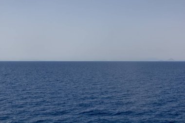 Uzakta adaları olan düz mavi deniz, Yunanistan