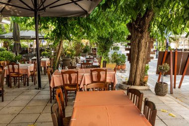 KALAVRYTA, GREECE - 2 Ağustos 2021: Yunanistan 'ın Mora yarımadasındaki Kalavryta' da açık hava restoranlarının masaları.
