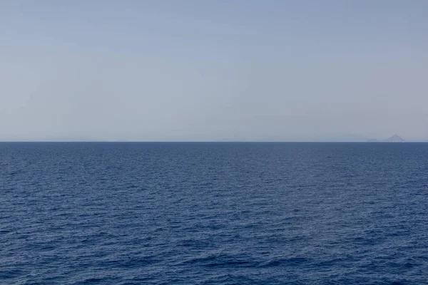 Uzakta adaları olan düz mavi deniz, Yunanistan