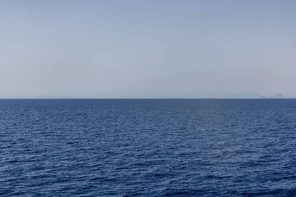 Uzakta adaları olan düz mavi deniz, Yunanistan