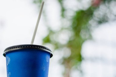 Buzlu kahve içme ve içecek konsepti için bulanık doğal zemin üzerine mavi kağıt bardak