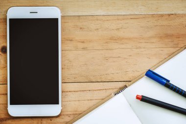 Smartphone, açılan bir defter ve kalem ahşap masa arka plan üzerinde iş ve teknoloji kavramı için