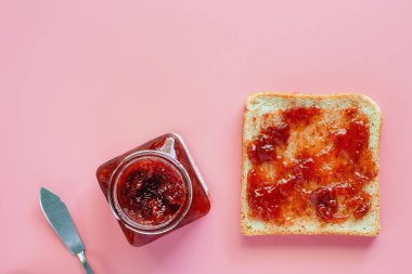 Gıda ve beslenme kavramı için pembe arka plan üzerinde yayılmış çilek ile ince kepekli ekmek dilimlenmiş