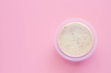 Gıda ve beslenme kavramı için pembe arka plan üzerinde plastik kabın içinde ev yapımı salata sosu