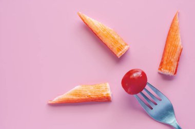 Çatal taze kırmızı domatese gıda ve kavram yemek için pembe arka plan üzerinde yengeç sopayla