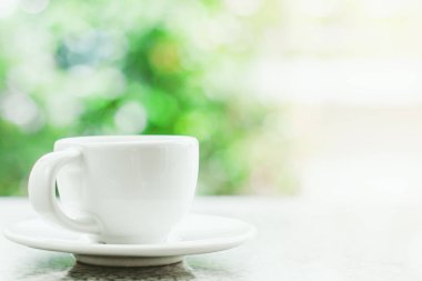 İçki ve içecek konsepti için bulanık doğal yeşil arka plan beyaz kahve fincanı