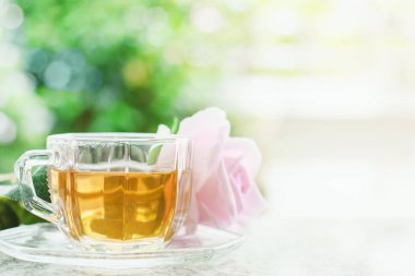 Çay ile içki ve içecek konsepti için bulanık doğal yeşil arka plana karşı tatlı pembe gül çiçek