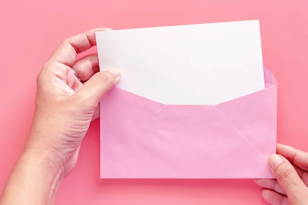 Mano Sosteniendo Blanco Tarjeta Papel Saludo Blanco Sobre Rosa Sobre —  Fotos de Stock