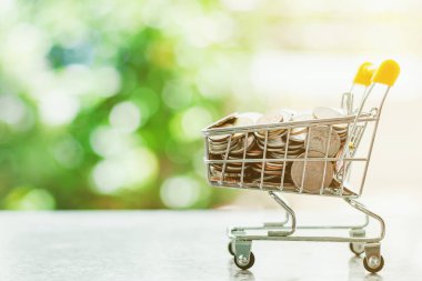 Küçük alışveriş arabasında ya da tramvayda para akışı bulanık yeşil arka planda iş ve finans konsepti için fotokopi alanı ile