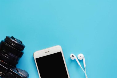 Fotoğraf makinesi akıllı telefon ve kulaklık üzerinde mavi arka plan ile medya teknoloji, seyahat ve dinlenme konsepti için