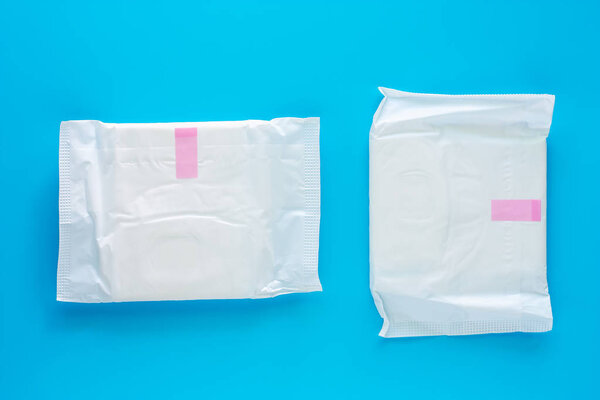 Feminine sanitary napkin, an absorbent item worn by a woman while menstruating, on blue background for hygiene and health concept