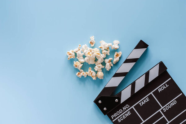 Movie clapper board with popcorn on blue background for entertainment concept