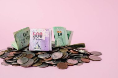 İş, finans, yatırım ve tasarruf kavramı için pembe arka planda Tayland para birimi banknotu ve para sikkeleri