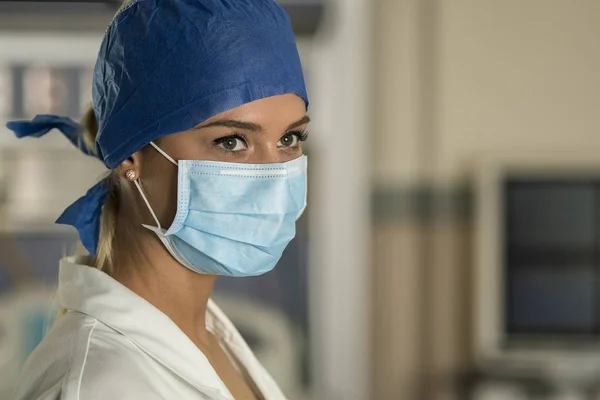 Genç sarışın hemşire acil odasında bir ameliyat maskesi ve cerrahi kap
