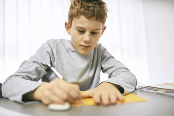 Schuljunge Schreibt Unterricht Auf Schreibtisch — Stockfoto