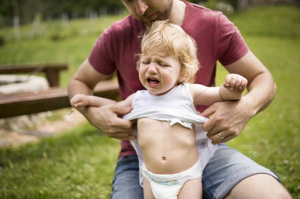 Vader Dressing Zijn Huilende Zoontje Tuin — Stockfoto