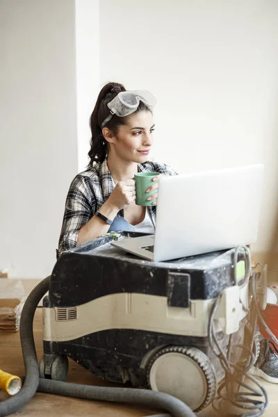 年轻女子装修她的新公寓 喝咖啡 看笔记本电脑 — 图库照片