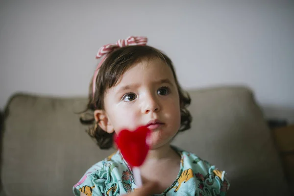 Schattig Baby Meisje Eten Een Hartvormige Lolly Thuis — Stockfoto