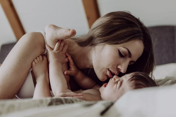 Mother Cuddling Kissing Baby Son Bed — Stock Photo, Image